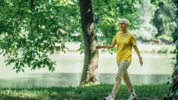 Femme âgée qui marche au bord d'un lac