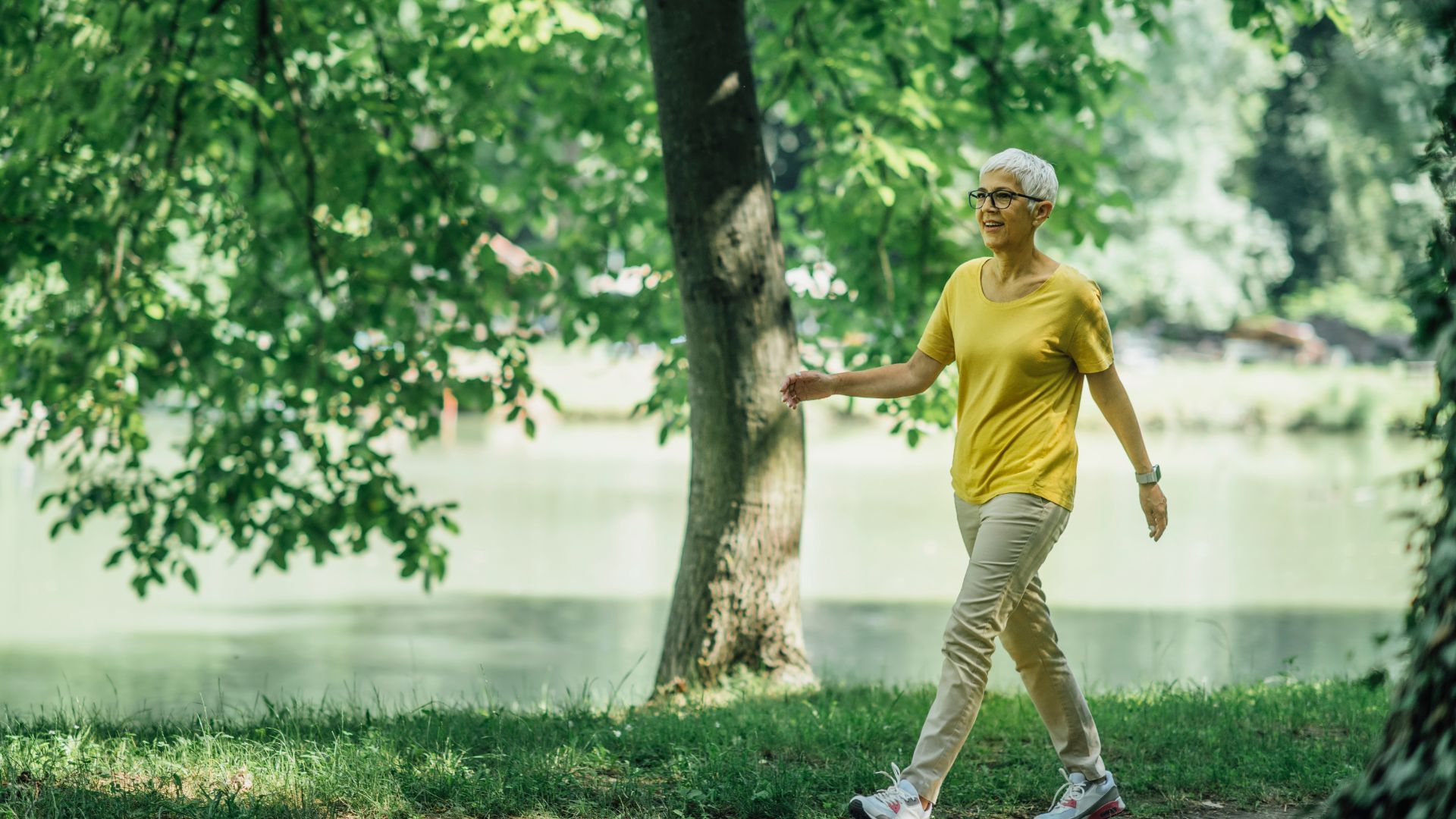 Femme âgée qui marche au bord d'un lac